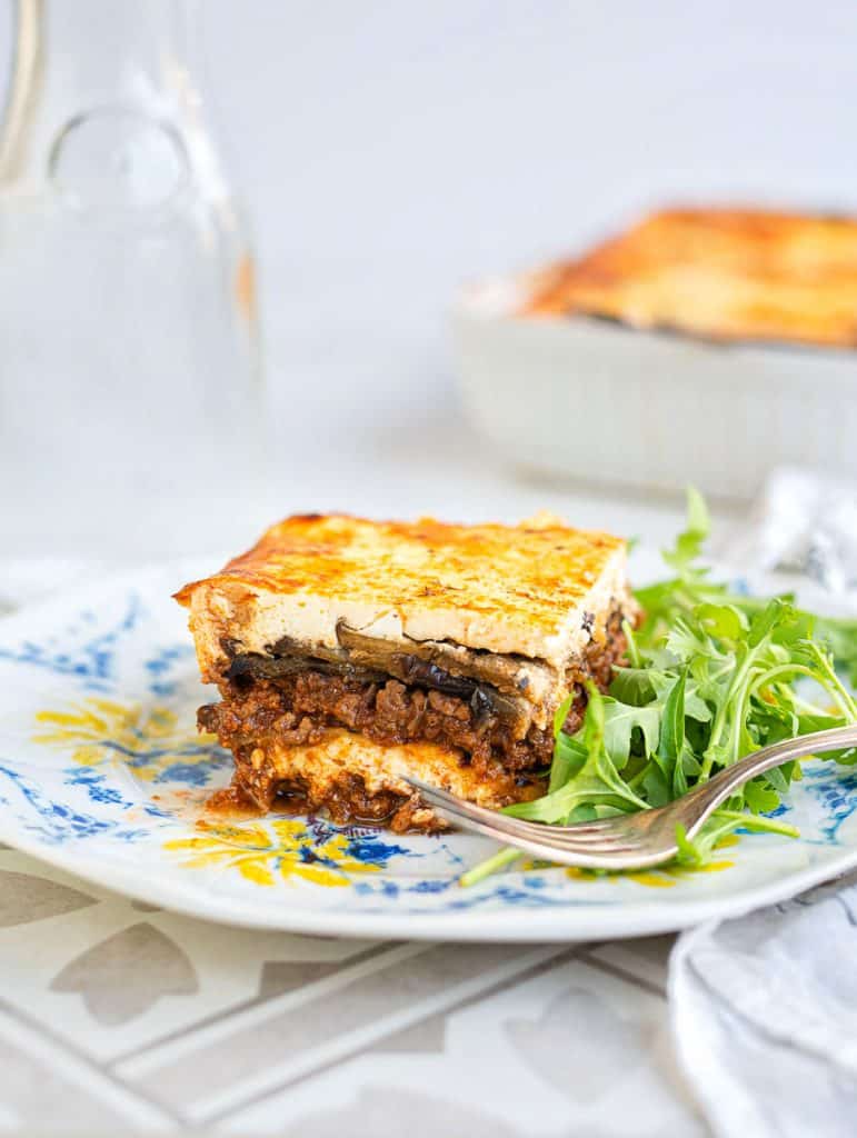 Slice of Moussaka on a plate with rocket salad