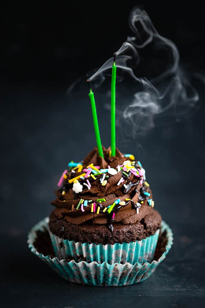 Chocolate cupcake with chocolate frosting and sprinkles with 2 candles