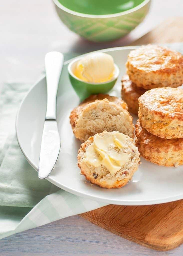 Cheese scones on a plate with one halved and spread with butter