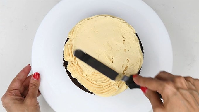 Smoothing caramel frosting over bottom cake layer