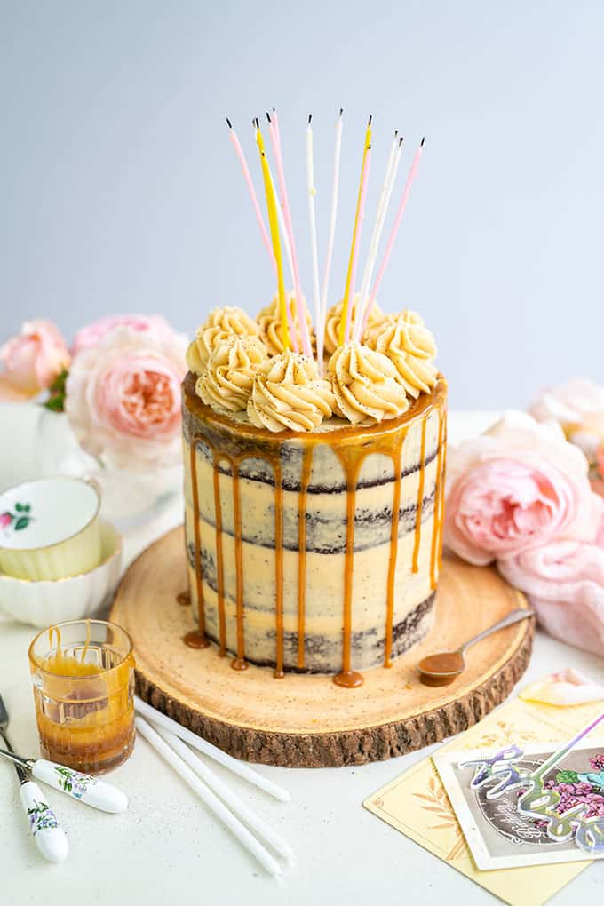 Salted Caramel Cake with caramel drip and candles on a rustic wood plate