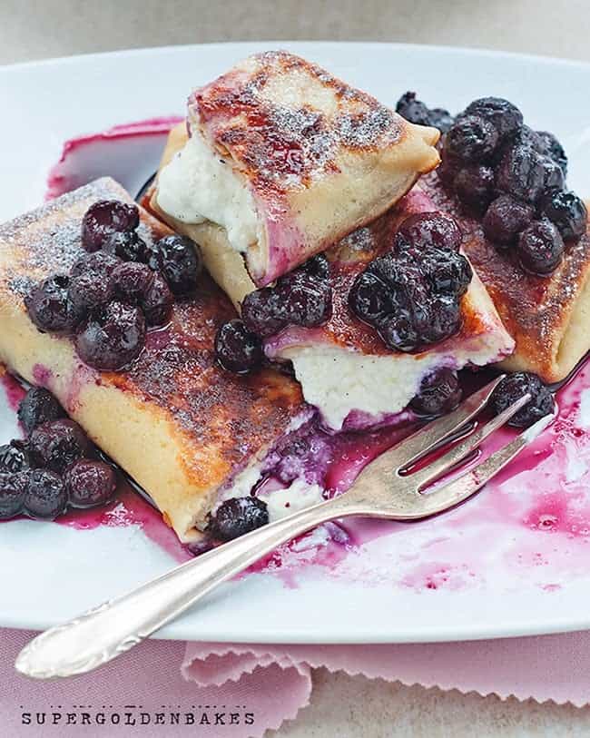 Blintzes filled with cheese and served with blueberry sauce on a plate