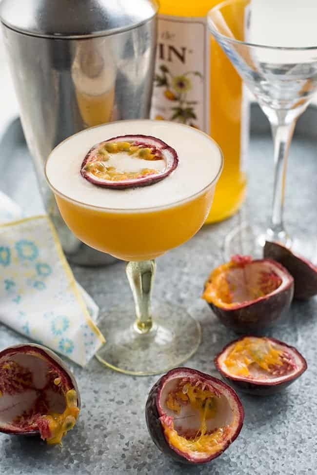 Passionfruit martini served in coupe cocktail glass with a thin slice of passion fruit on a metal tray