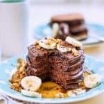 Stack of chocolate pancakes with bananas and nuts