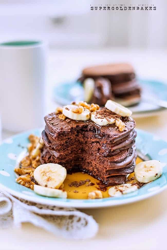 Stack of chocolate pancakes with bananas and nuts