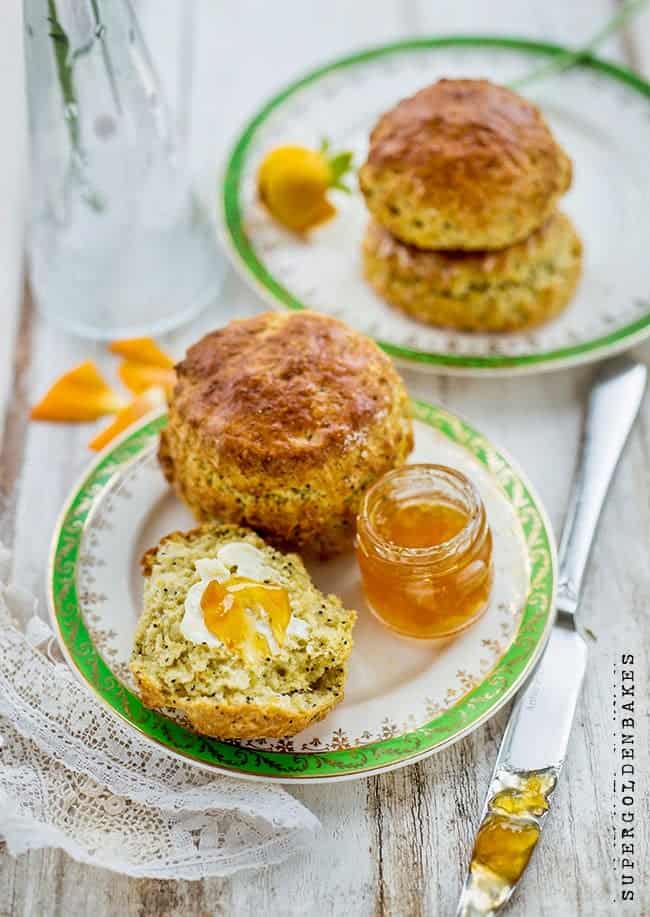 Orange poppyseed scones on a plate with one split and buttered