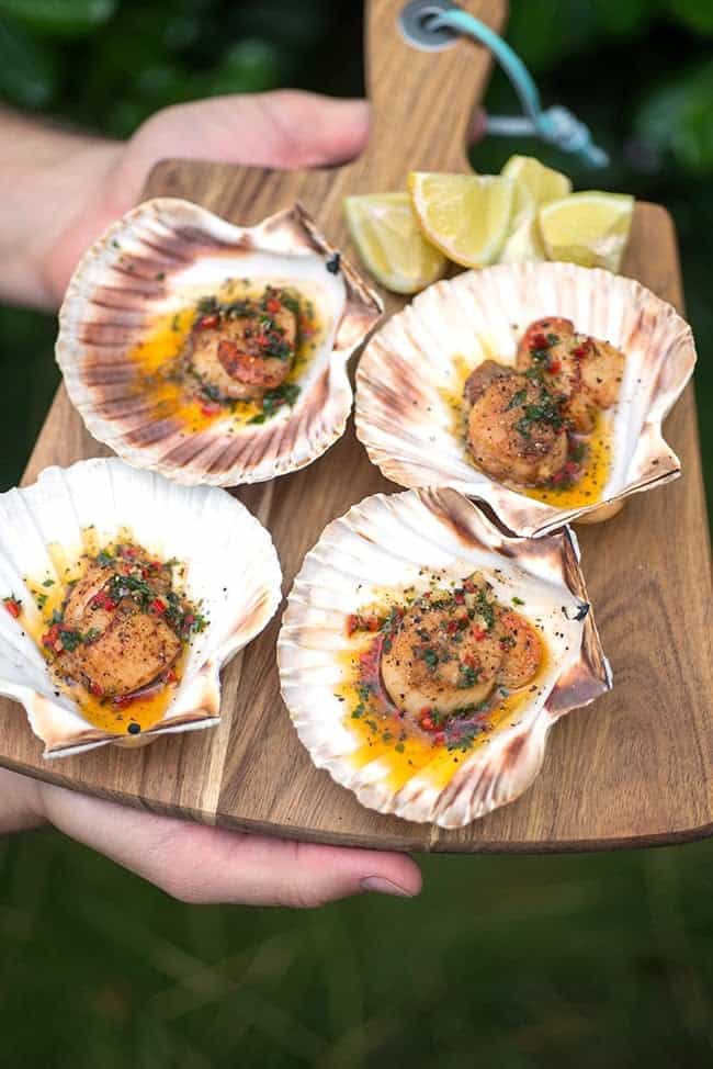 Serving scallops with butter sauce on a wooden board