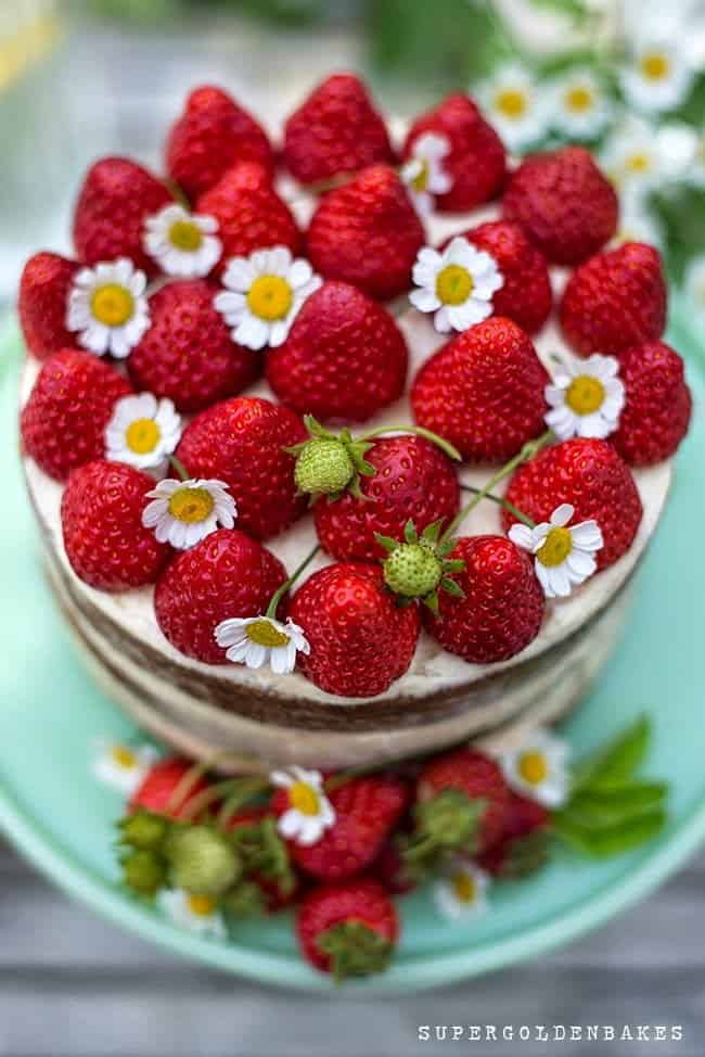 Close up on a layer cake topped with whole fresh strawberries