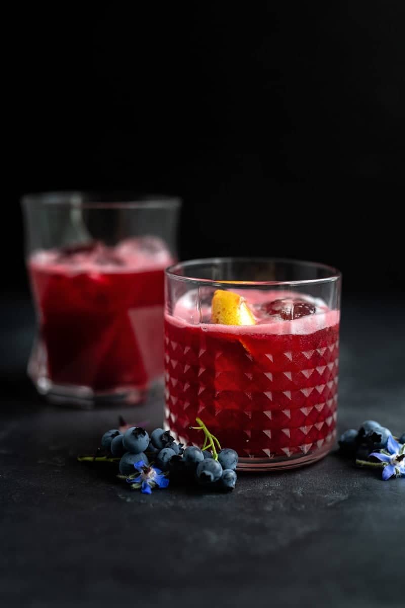 Blueberry gin sour cocktail in a rocks glass with ice
