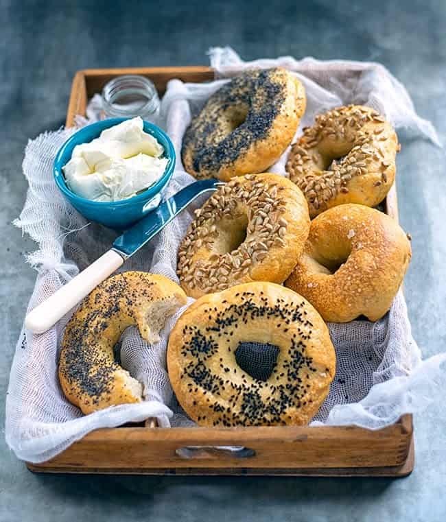 Tray of homemade bagels with bowl of cream cheese on the side