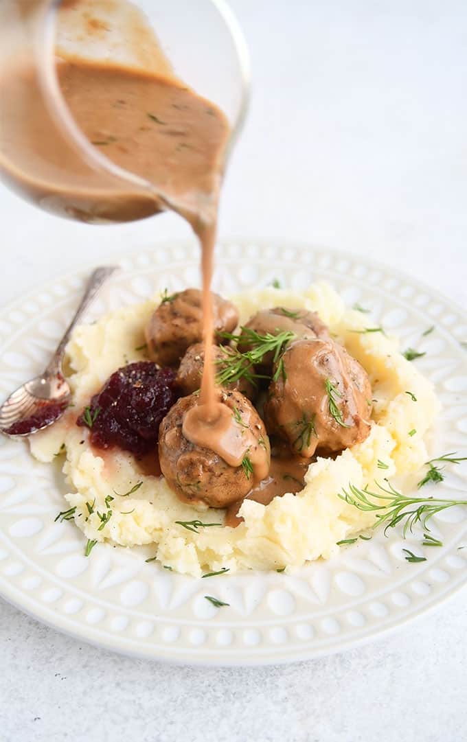 Pouring gravy over Swedish meatballs served over mashed potatoes