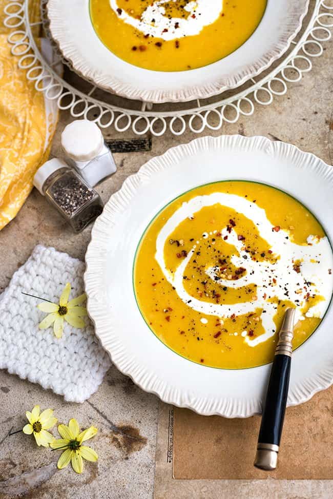 two bowls of curried parsnip soup drizzled with coconut cream