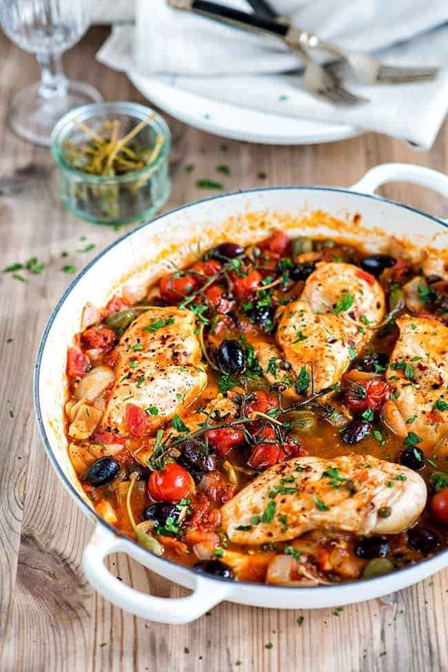 chicken breasts cooked with tomatoes olives capers and anchovies in a shallow cast iron casserole