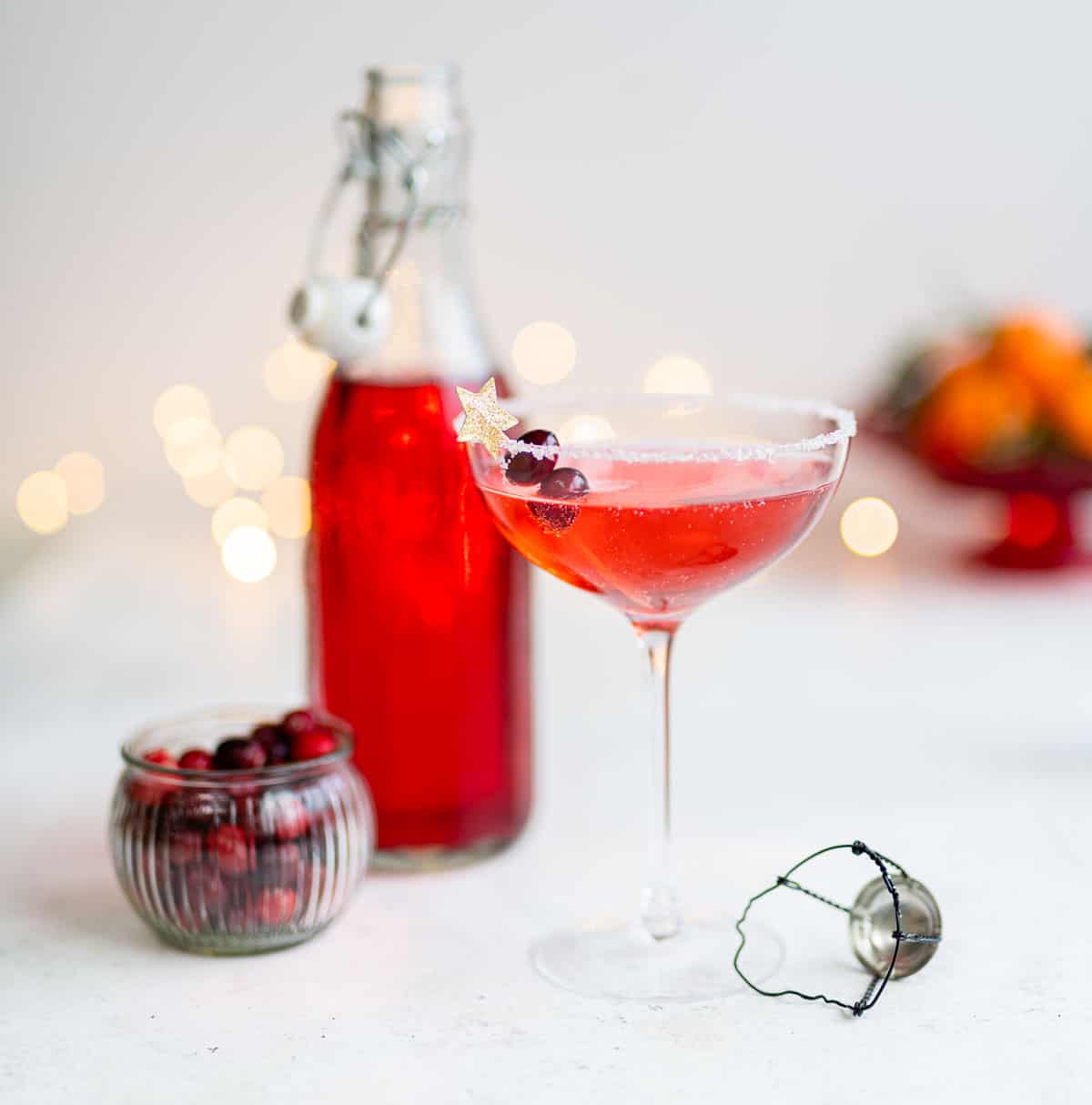Cosmopolitan cocktail in a champagne coupe garnished with fresh cranberries 