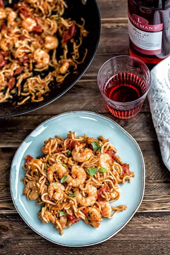 Plate of prawn noodles with a glass of rose wine on a rustic background