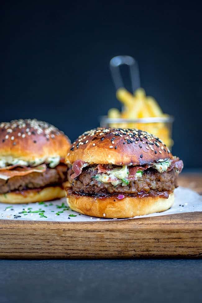 Close up on blue cheese burgers served in brioche buns with pancetta and cheese