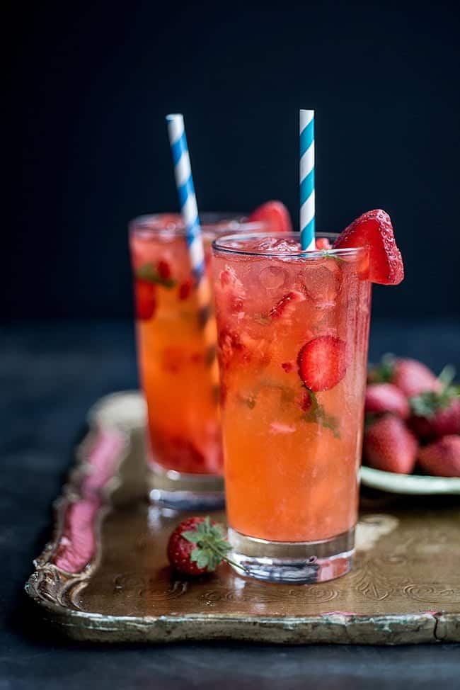 Strawberry Moscow Mule in two tall glasses garnished with fresh strawberries