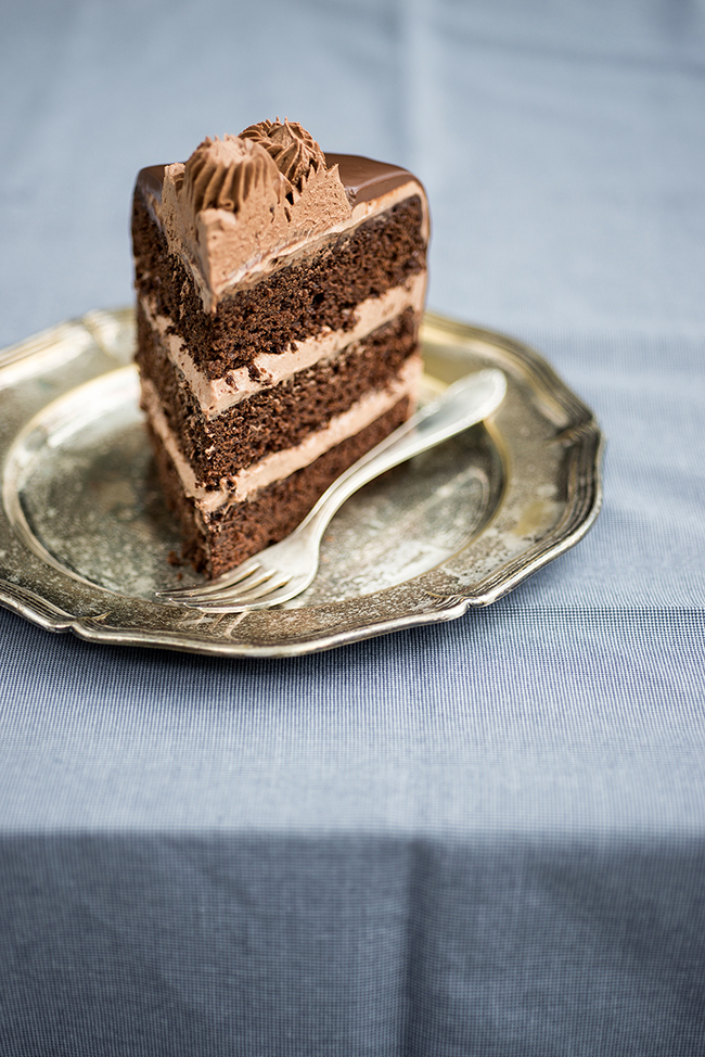 Slice of the Ultimate Chocolate Cake with Nutella filling and frosting on a metal plate