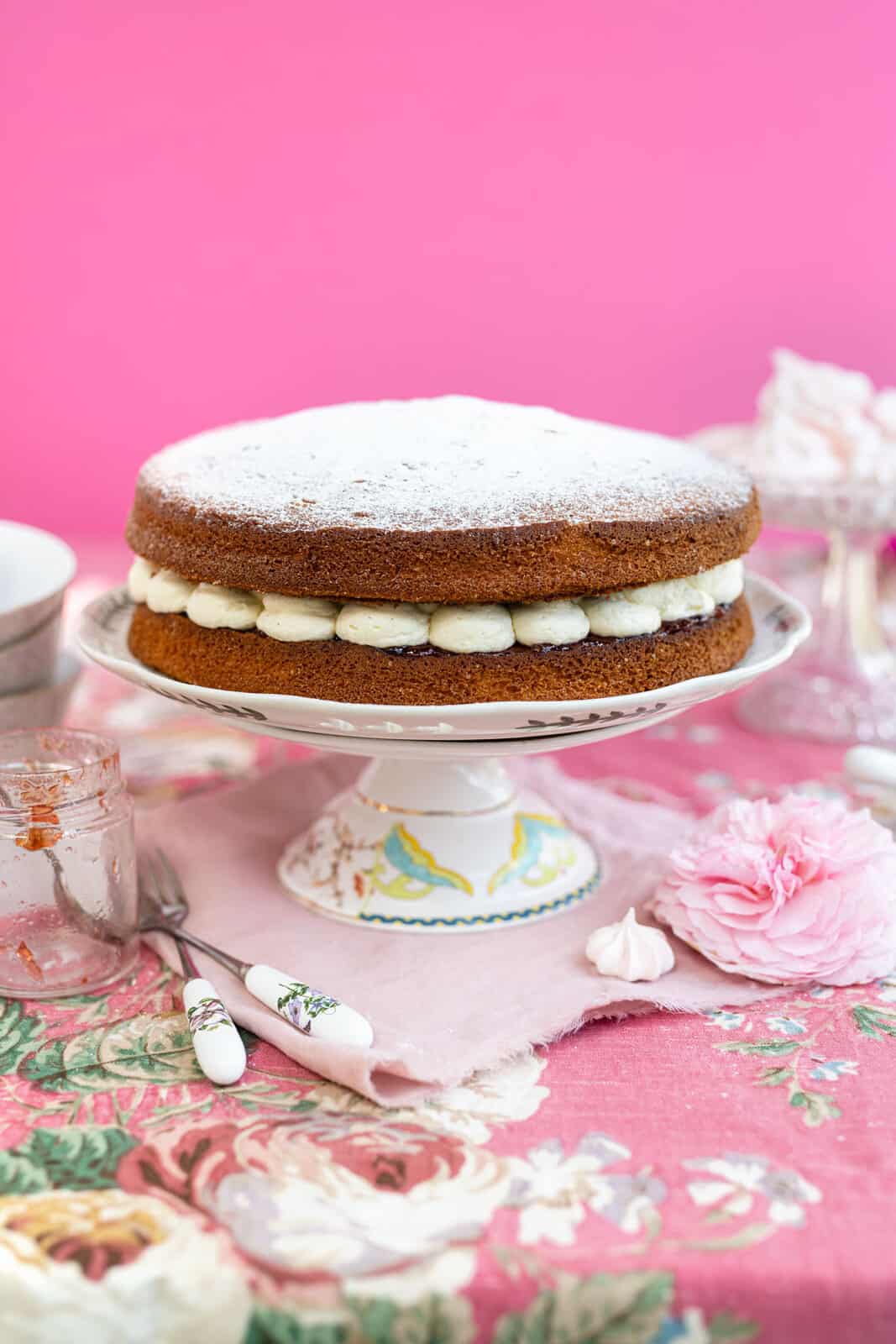 Classic Victoria sponge cake filled with jam and whipped cream on a cake stand