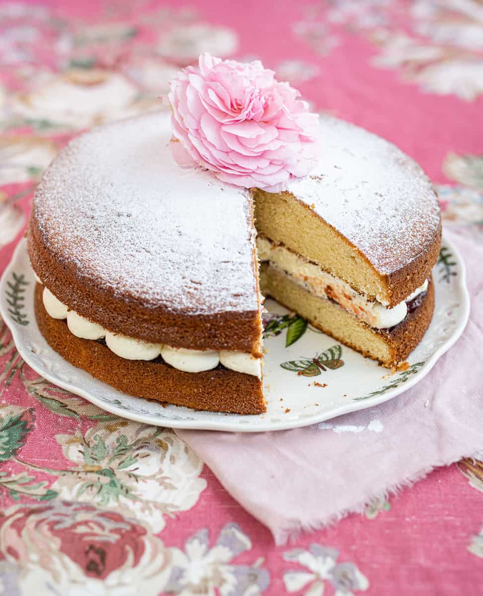 Sliced Victoria Sandwich cake decorated with a fresh rose