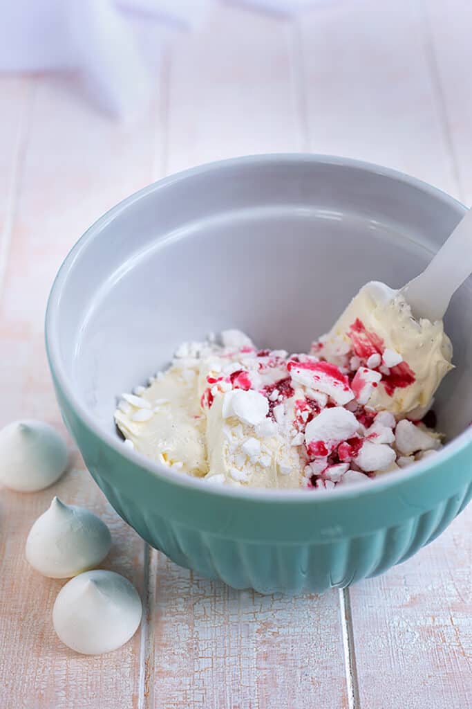 folding meringue and berries into whipped cream