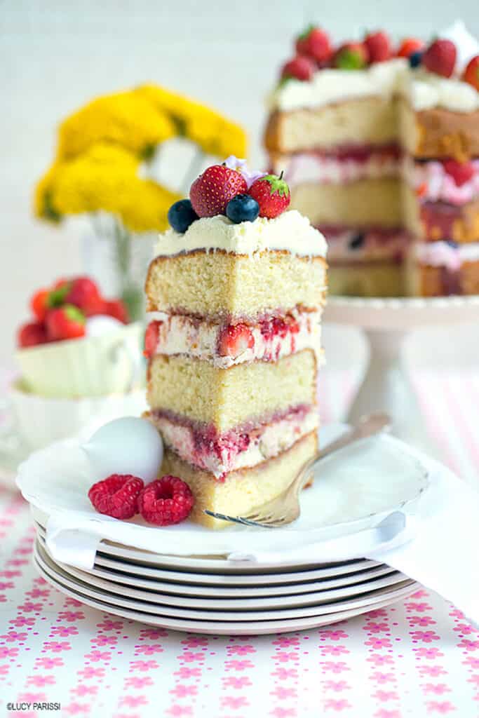 Slice of Eton mess cake with strawberries, raspberries and blueberries on a pretty flower patterned background