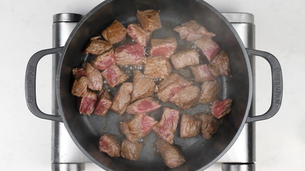 searing beef cubes in a pot