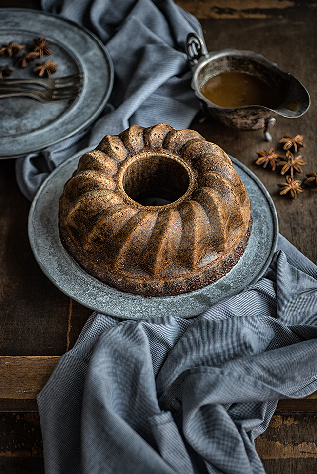 Gingerbread Bundt Bake on a metal plate with toffee sauce on the side 