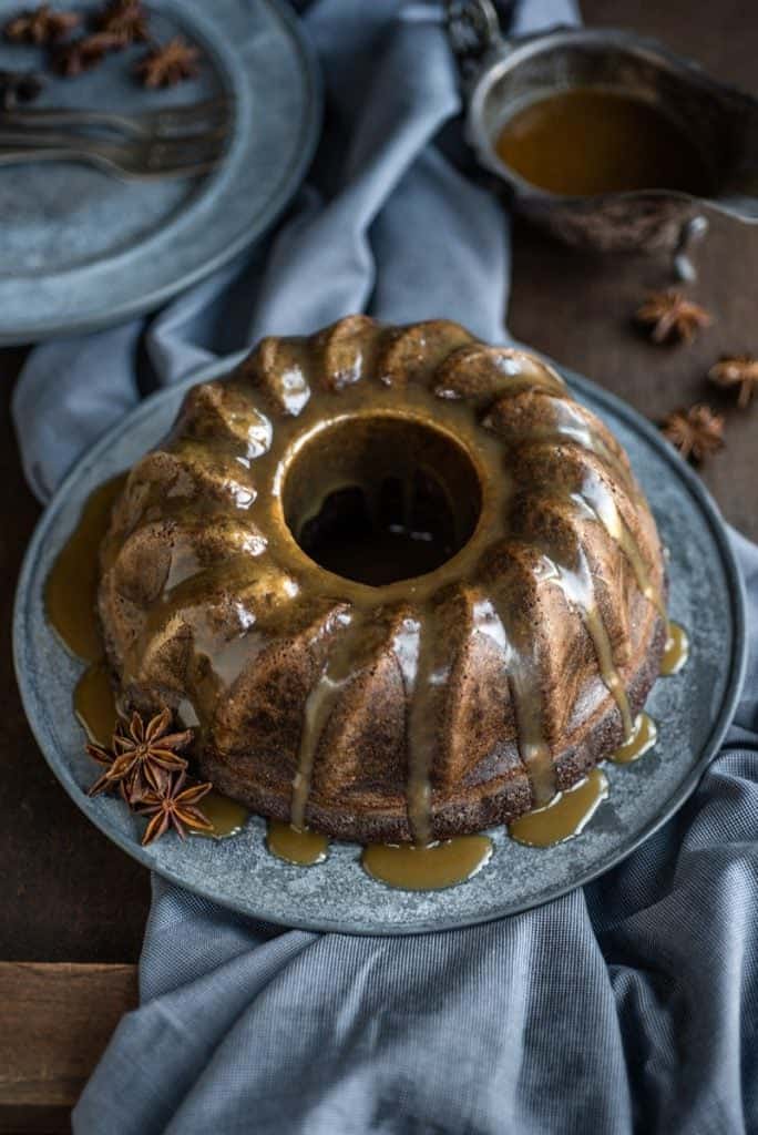 Gingerbread bundt cake drizzled with toffee sauce on a metal plate