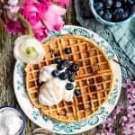 These buttermilk blueberry waffles are crisp on the outside and fluffy on the inside. Serve with whipped coconut cream for an indulgent breakfast.