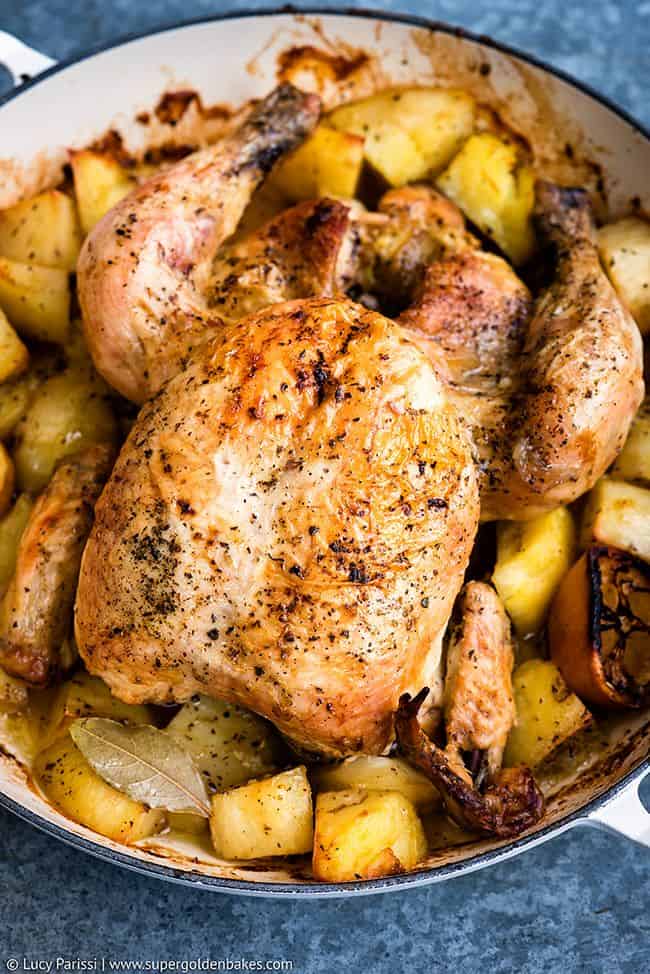 Golden Greek Roast Chicken in a large casserole with roast potatoes
