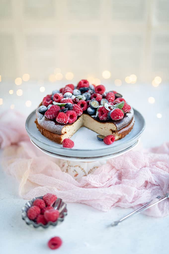 Quark cheesecake topped with fresh berries on a cake stand