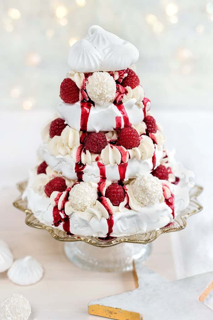 Meringue Christmas tree with whipped coconut cream, raspberries and white chocolate truffles drizzled with mulled berry coulis