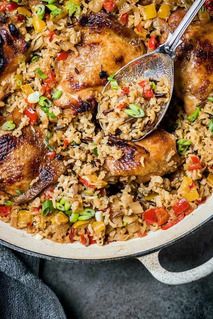 Chicken thighs cooked with rice and peppers in a shallow cast iron casserole