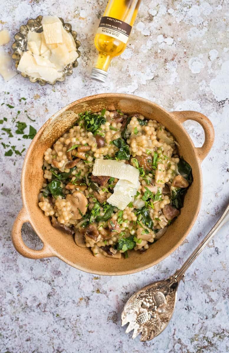 Pearl couscous risotto with mushrooms and spinach served with shavings of Parmesan