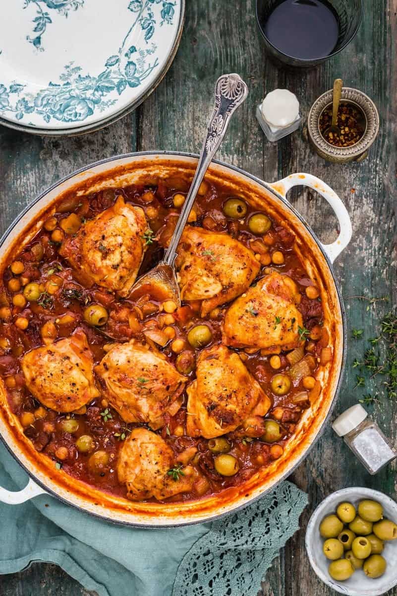 Chicken stew with olives and chickpeas in a large shallow cast iron casserole
