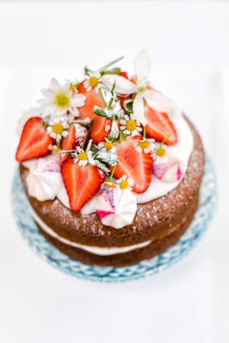 Vegan vanilla cake with whipped coconut cream – perfect for birthdays and celebrations and embarrassingly easy to make! Decorate with fresh strawberries and flowers.