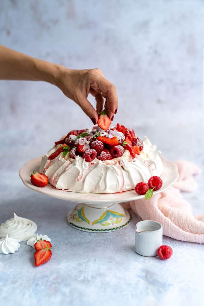 Decorating a Pavlova withs strawberries and raspberries