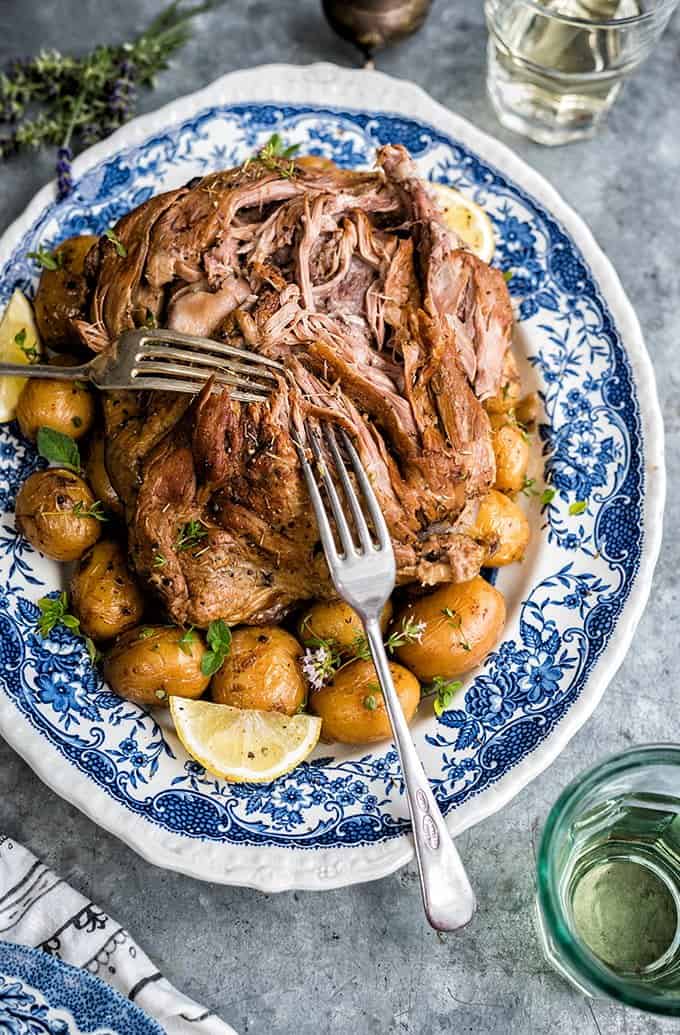 Platter of tender slow cooked Greek Lamb with two forks pulling apart