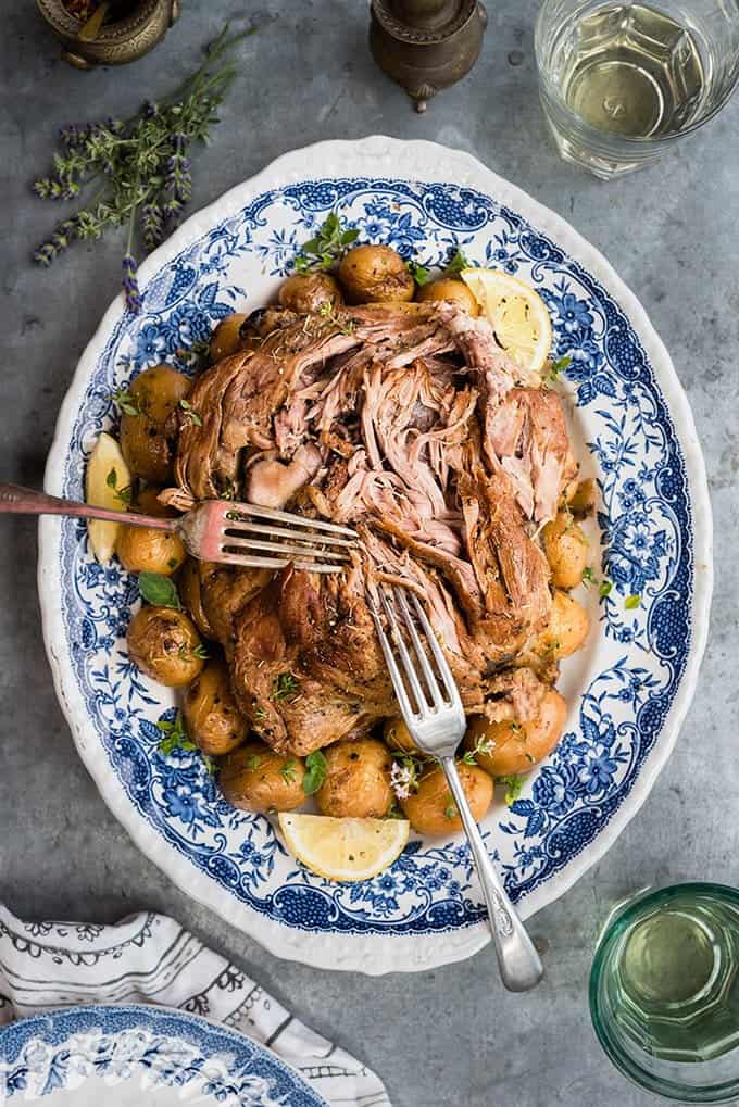 A platter of slow cooked Greek lamb and potatoes on a blue platter