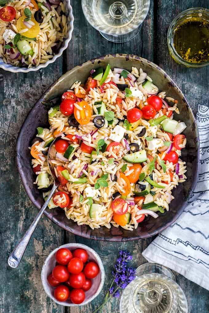 Overhead shot of Greek orzo pasta salad in a bowl with tomatoes, pepper, cucumber, feta and olives