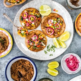 Tender and delicious bourbon and coke pulled pork served on tostadas with quick sweetcorn salsa and pickled onions. This recipe makes a big batch of pulled pork which you can serve in a variety of ways.