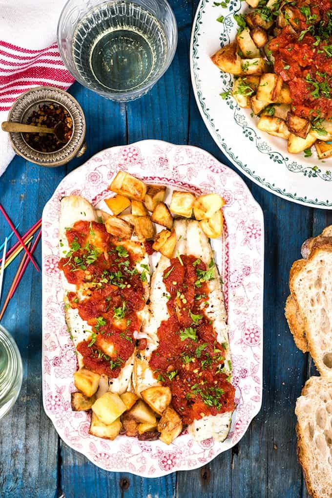 Summery Spanish oven-baked patatas bravas with seas bass. The potatoes make a great starter to share or turn them into a main with the fish.
