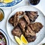 Grilled lamb chops served on a plate with lemon wedges