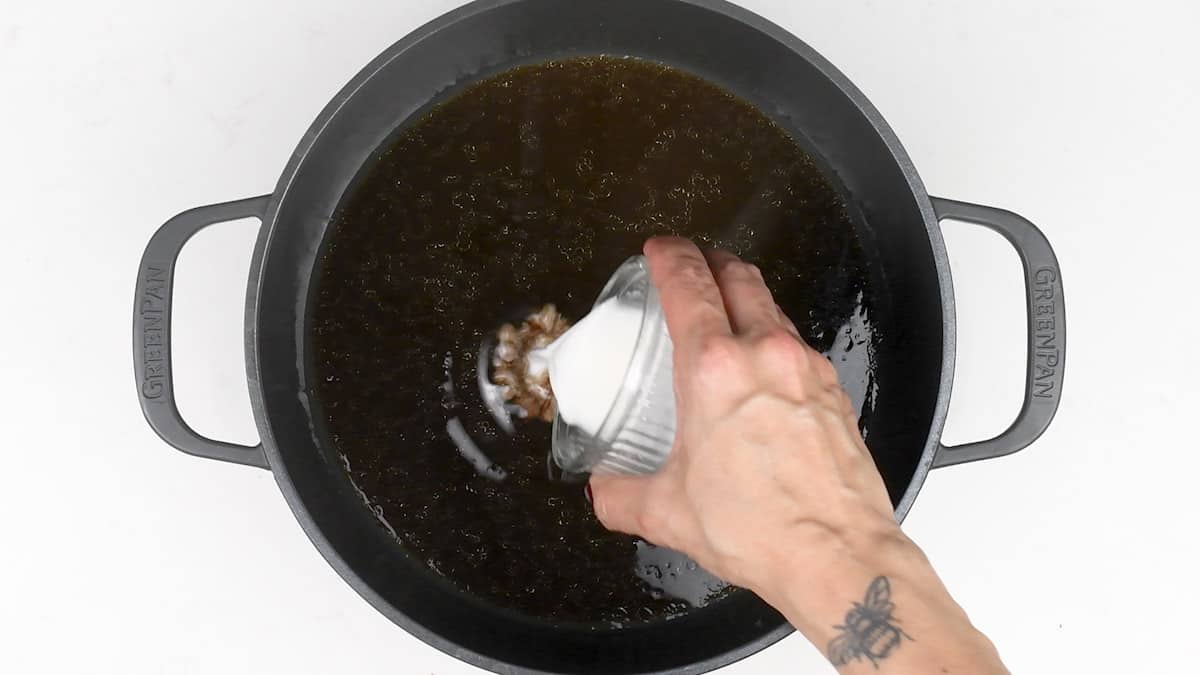 Adding cornflour slurry to lamb gravy in pot