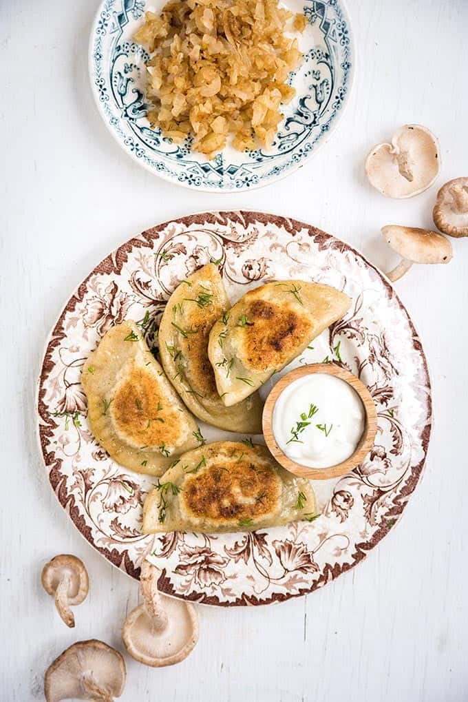 Plate of Polish Pierogi served with sour cream and fried onions