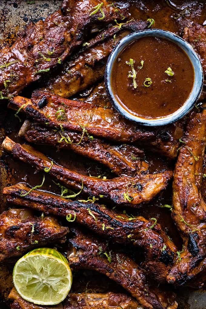 Overhead close up on Korean pork spare ribs with lime zest and spicy sauce on the side