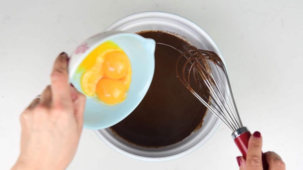 Adding egg yolks to melted chocolate in a bowl