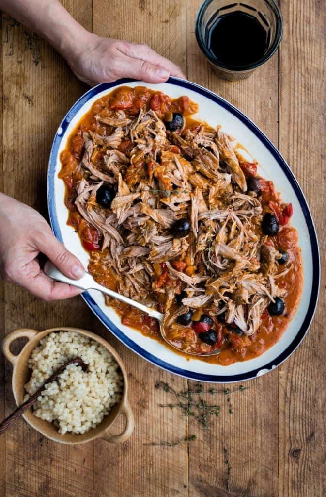 Platter of pulled shredded lamb with tomato sauce and black olives