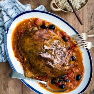 Slow cooked lamb shoulder in rich tomato sauce with olives and anchovies served on a platter
